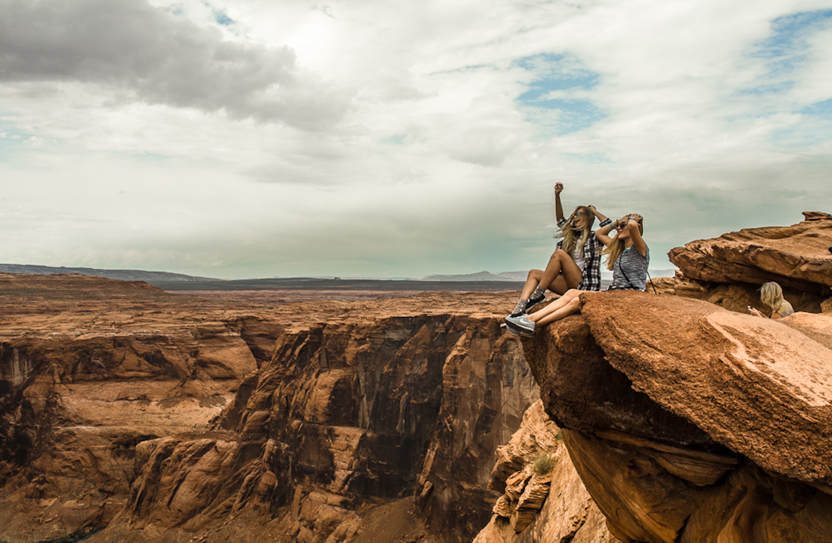 Dwie młode dziewczyny siedzą na skale podziwiając panoramę Horshoe Bend.