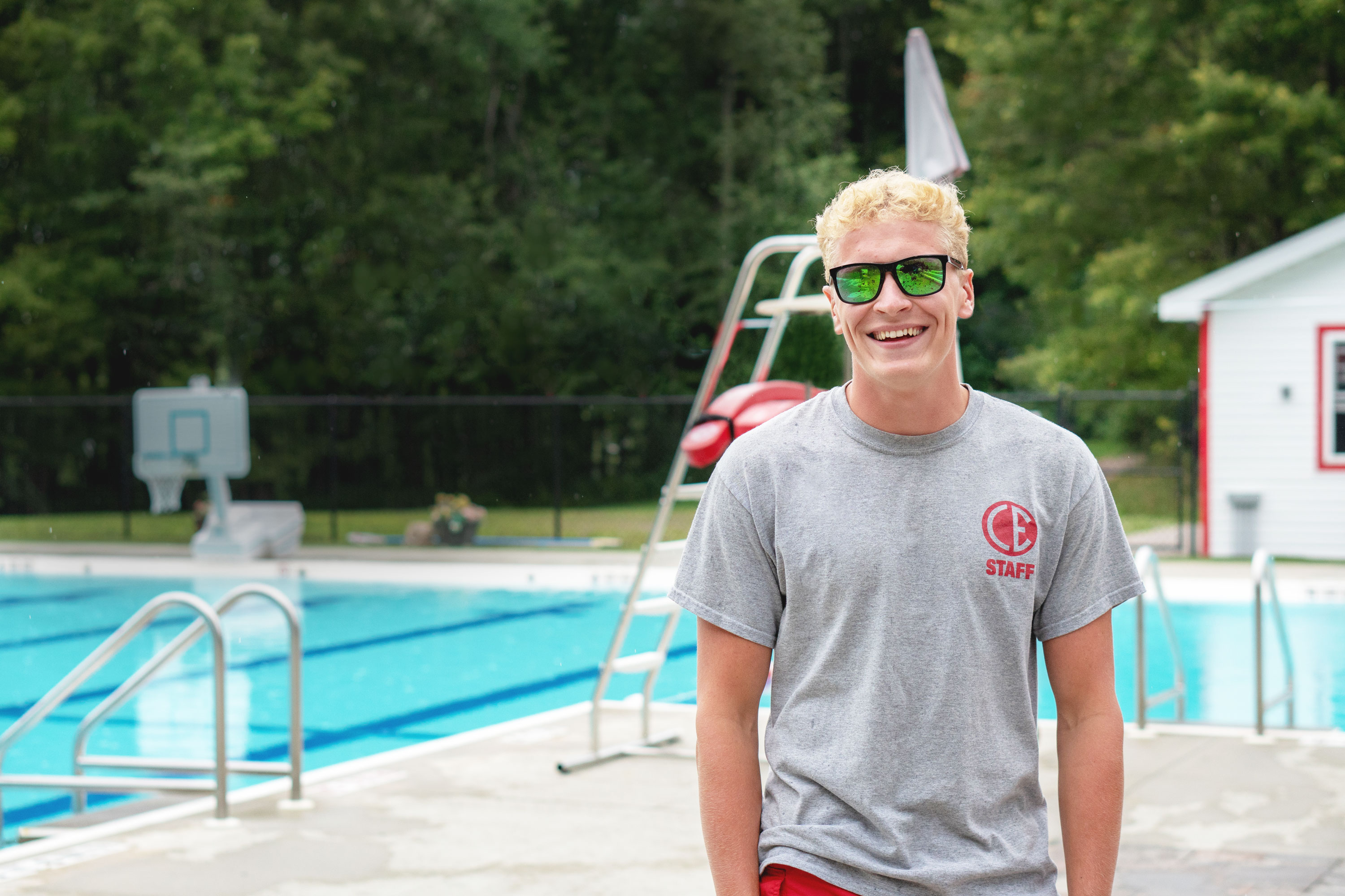 A student lifeguard next to a pool at summer camp.