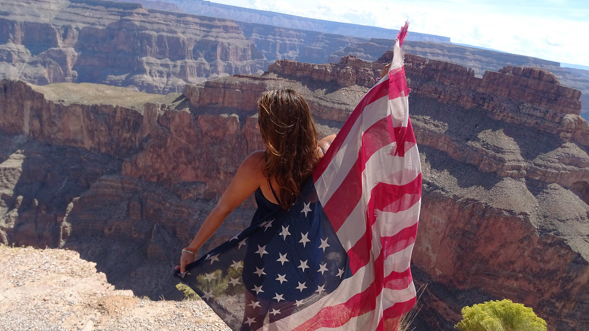 Uczestniczka programu Camp Leaders podziwia Grand Canyon trzymając amerykańską flagę.